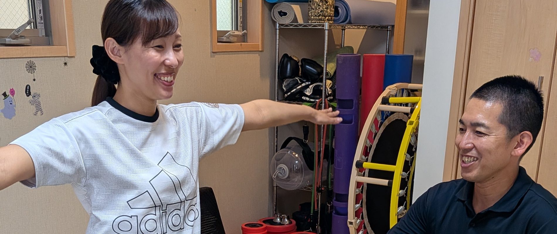 まちの隠れ家ジム宿河原で、バランスボールに座って笑顔で運動する様子